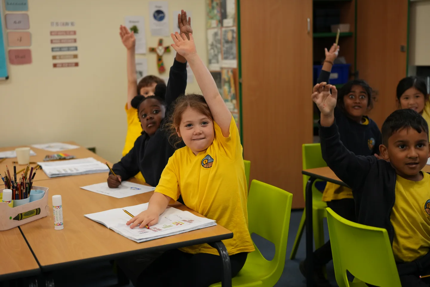 St John’s pupils raising their hands enthusiastically in their classroom